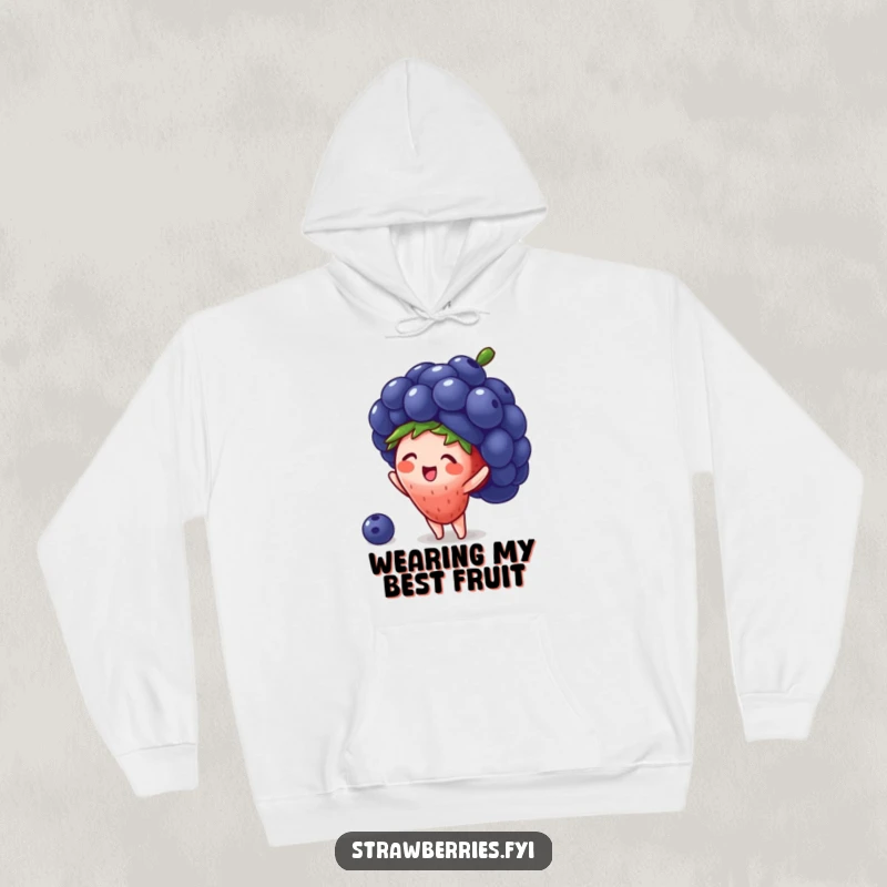 Funny hoodie depicting a tiny strawberry character gleefully attempting to wear a large blueberry as a hat, celebrating cute fashion.